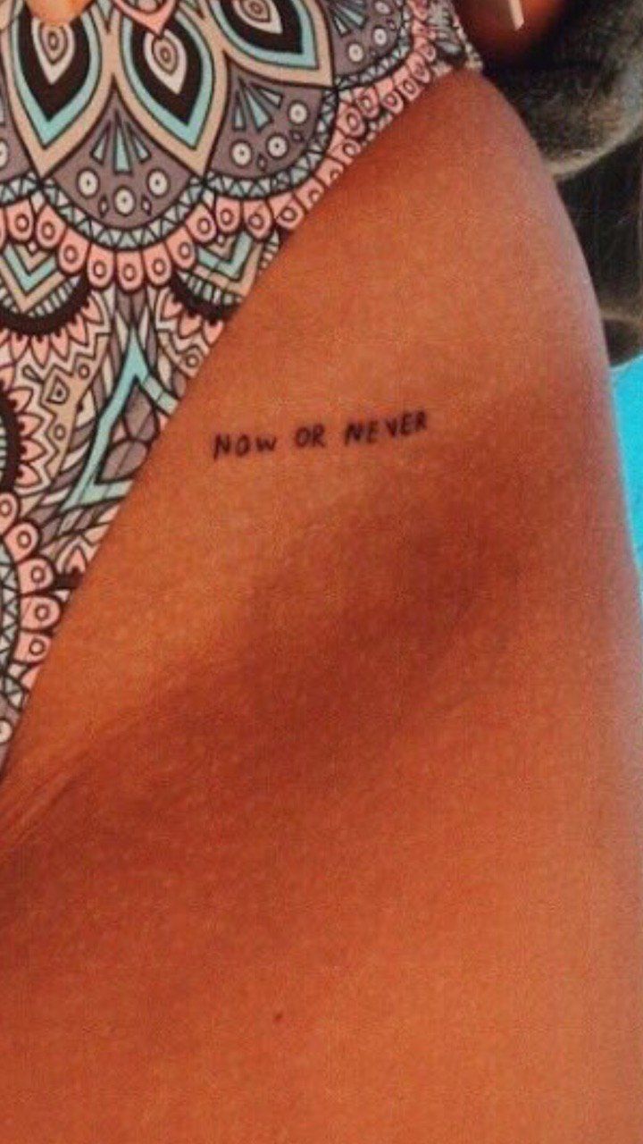 the back of a woman's stomach with a tattoo saying now or never on it