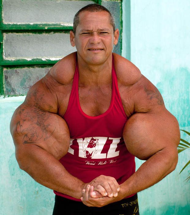 a man in red shirt and black shorts posing with his hands on his hips while looking at the camera