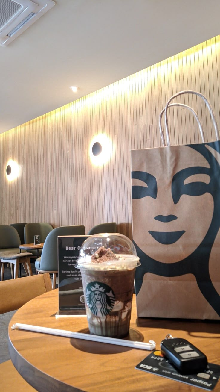 a starbucks bag sitting on top of a wooden table next to a cup of coffee