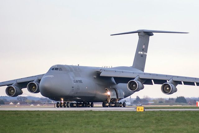 a large air plane sitting on top of an airport tarmac next to a field