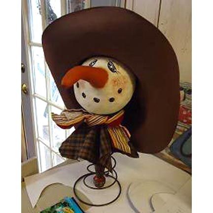 a stuffed animal wearing a brown hat and scarf on top of a white table next to a window