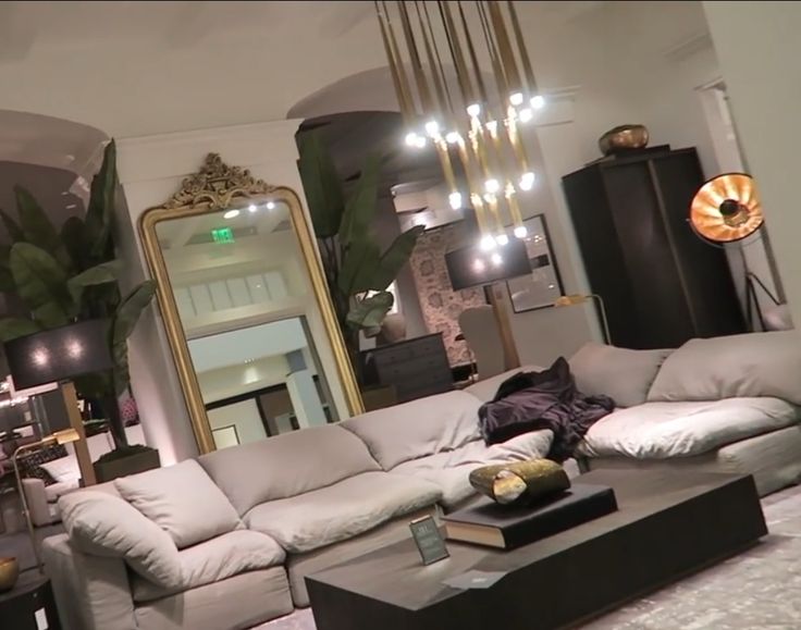 a living room filled with furniture and a large mirror hanging from the ceiling above it