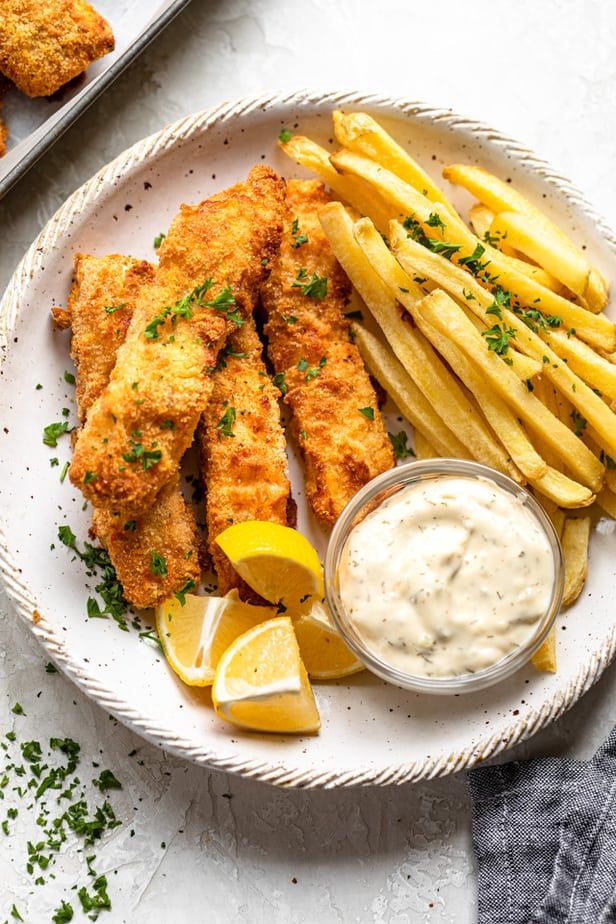 fish and fries on a plate with lemon wedges