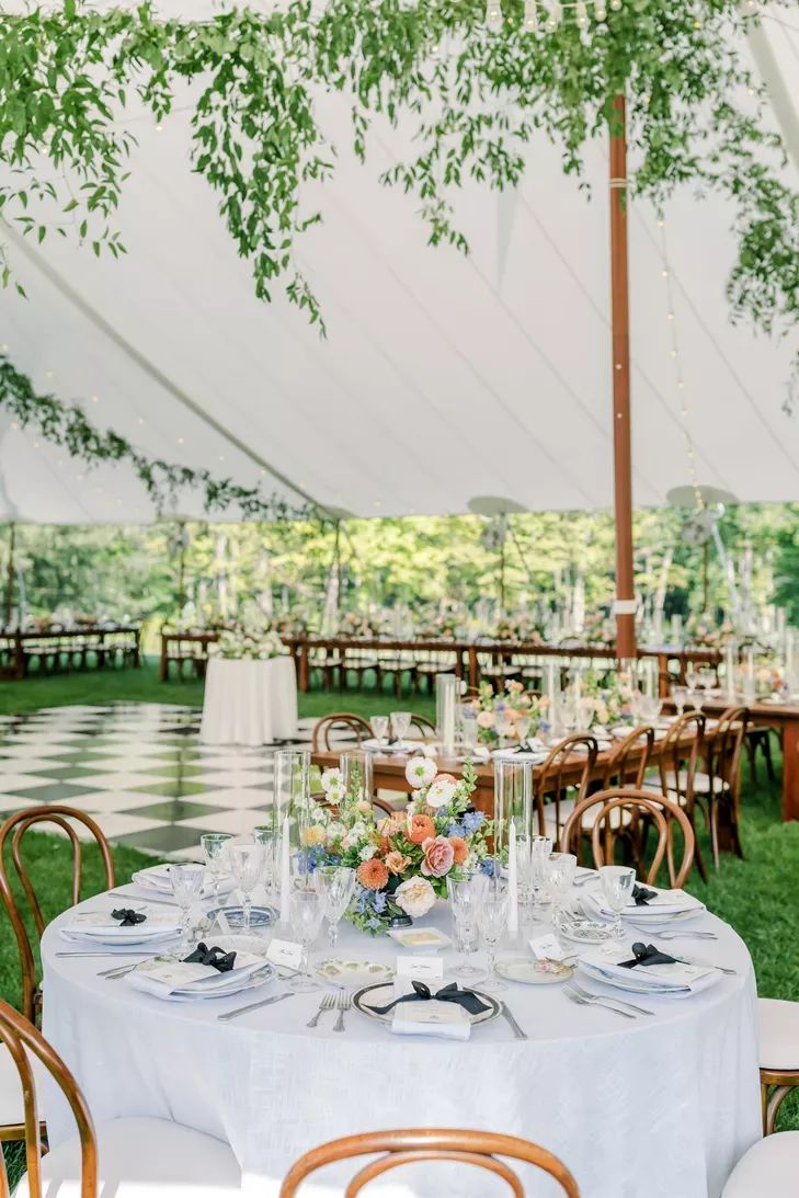 an outdoor tent with tables and chairs set up for a wedding reception in the grass