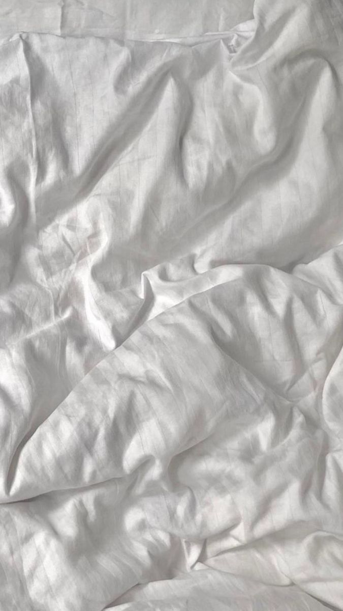 an unmade bed with white sheets and pillows