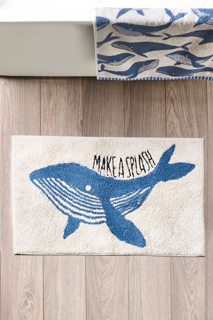 a bathroom rug with a blue whale on it and the words make a splash printed on it