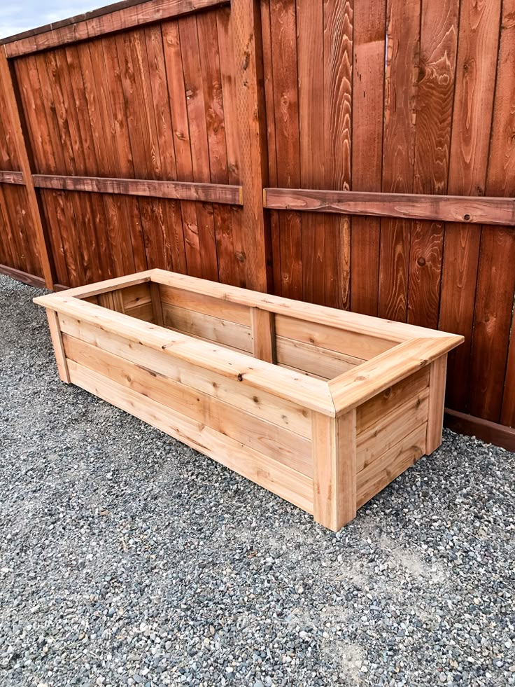 a large wooden planter sitting on top of gravel