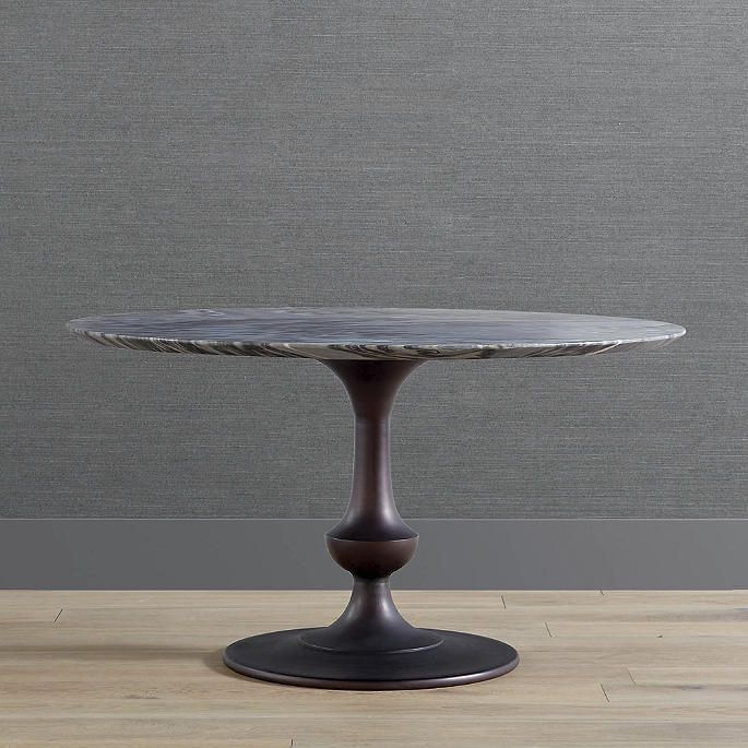 a small round table on a wooden floor in front of a gray wall and wood floors