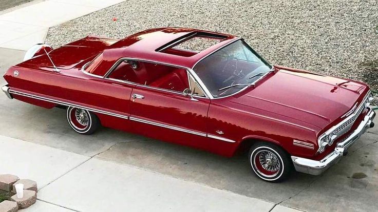 an old red car is parked on the sidewalk