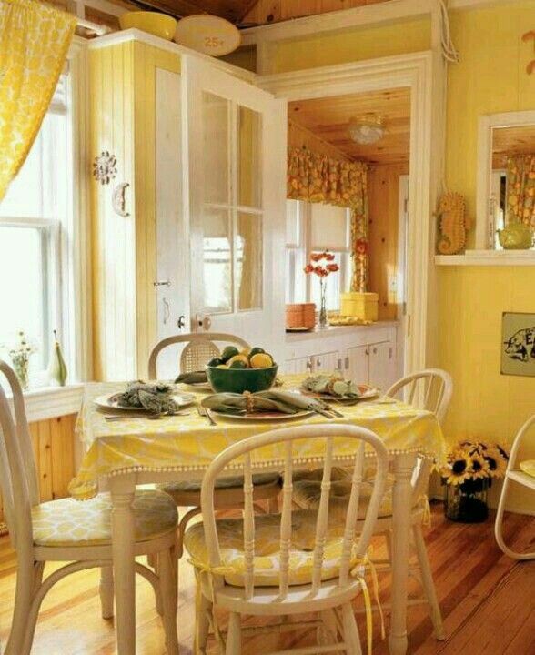 a dining room with yellow walls and white chairs around a table in front of a window