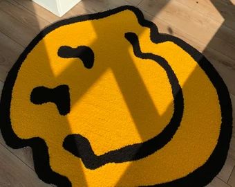 a yellow and black smiley face rug on the floor