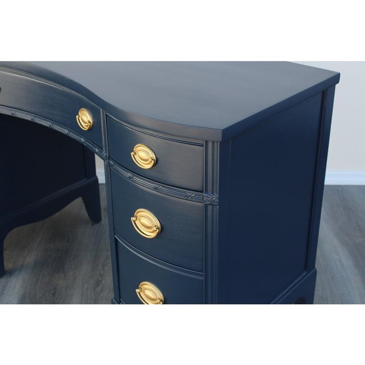 a black desk with gold handles and drawers