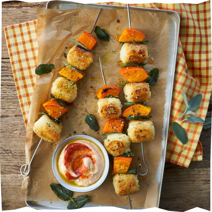 several skewers of food on a tray with dipping sauce