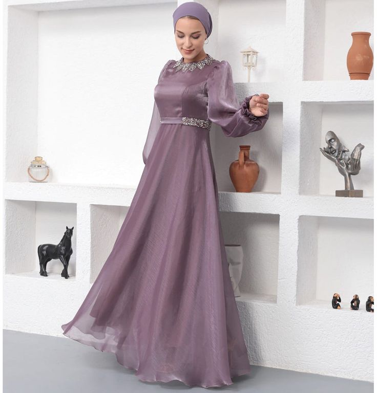 Modest Formal Satin Dress G531 Lilac ATTENTION: This item has a special return policy, different from our regular store policy. See details below. A classy evening dress perfect for formal events! Features a gemmed petal design along the neckline, puffed sleeves, and is made with sleek satin. FEATURES: - Fully lined - Satin fabric with organza overlay - Gemmed petal design along neckline - Puffed sleeves with a small flare at the wrist - Matching satin waistband with glitter along sides FABRIC Satin fabric made from 100% Polyester. Weighs about 2 lbs CARE: Dry clean only Do not machine wash Do not machine dry Do not bleach Made in Turkey SPECIAL RETURN POLICY FOR EVENING GOWNS The following return policy applies on all evening gowns: • Return must be requested within 48 hours of receiving Formal Satin Dress, Thobes Men, Classy Evening Dress, Organza Overlay, Sports Hijab, Small Wall Decor, Eid Party, Islamic Wall Decor, Modest Swimsuits