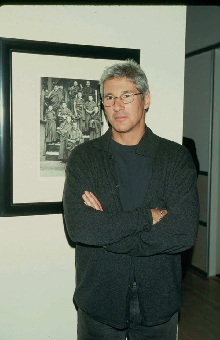 a man standing with his arms crossed in front of a black and white photo on the wall