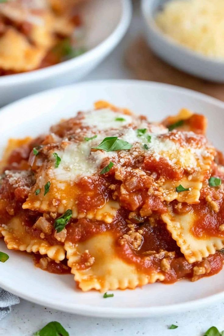 a white plate topped with lasagna sauce and meat covered in parmesan cheese