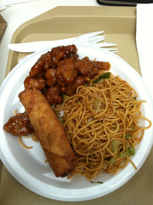 a white plate topped with noodles and meat next to a fork on top of a tray