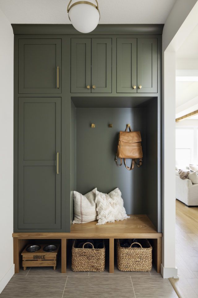 an entryway with green painted cabinets and baskets on the bench in front of it