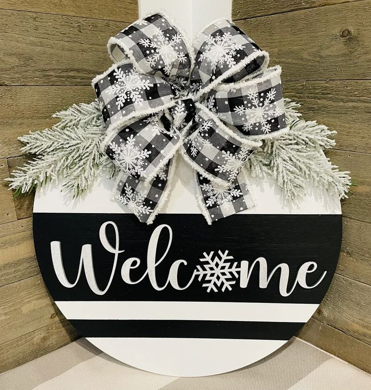 a welcome sign hanging on the side of a wooden wall with snowflakes and evergreens