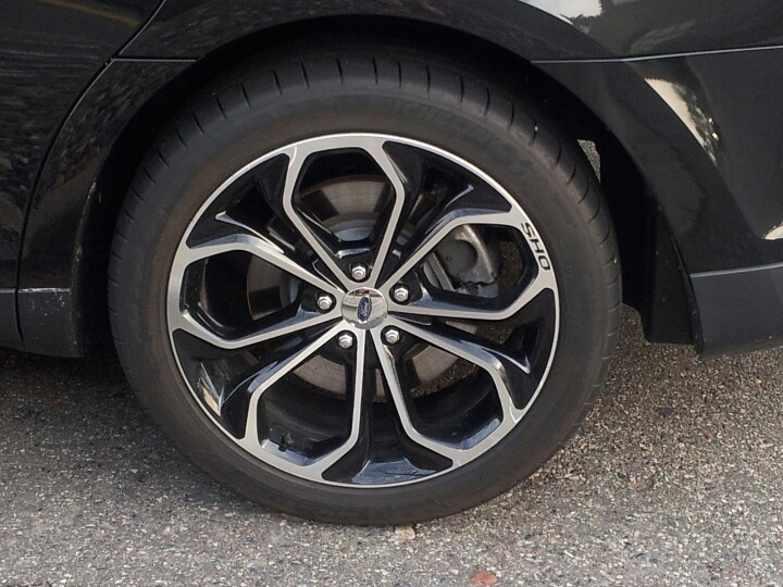 the front wheel of a black car parked in a parking lot