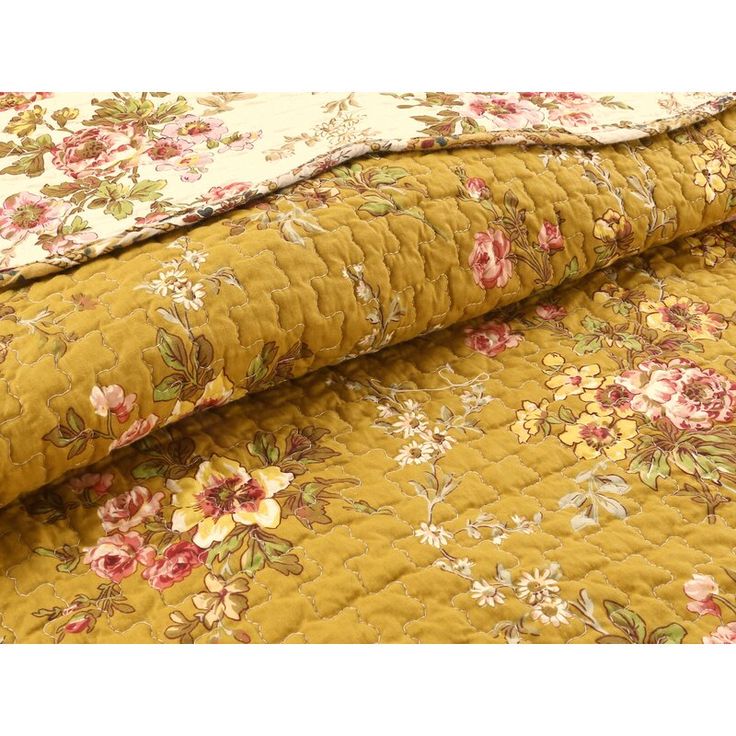 a yellow floral quilted bed spread with pink and white flowers on the bottom half