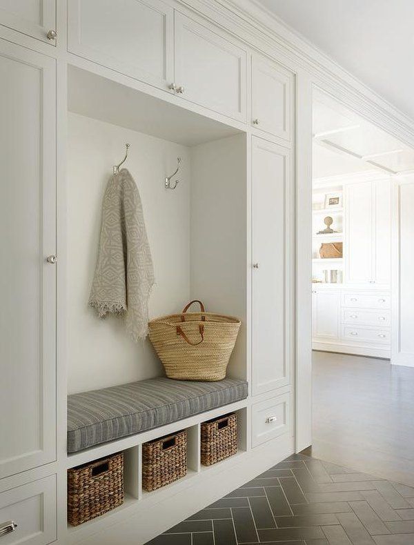 a basket and coat hanger in a white entryway with built - in cabinets