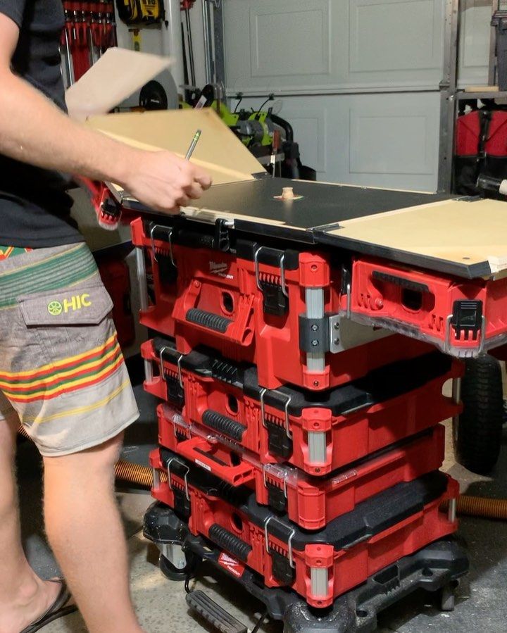 a man standing next to a stack of red tool boxes in a garage with tools on it