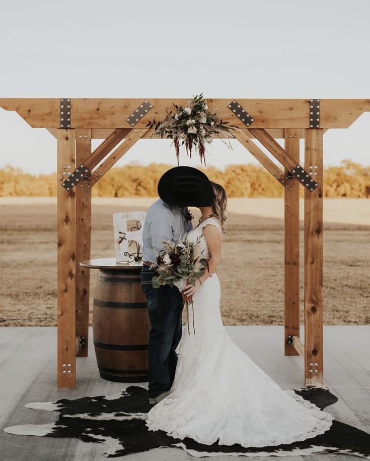 a bride and groom standing in front of a barrel