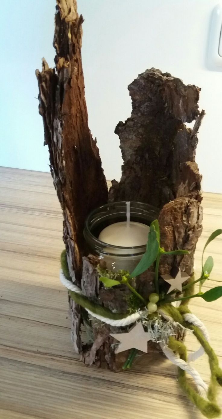 a candle holder made out of wood and branches with leaves on the top, sitting on a wooden table