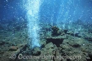 an underwater view of the ocean floor with blue water and bubbles coming out of it