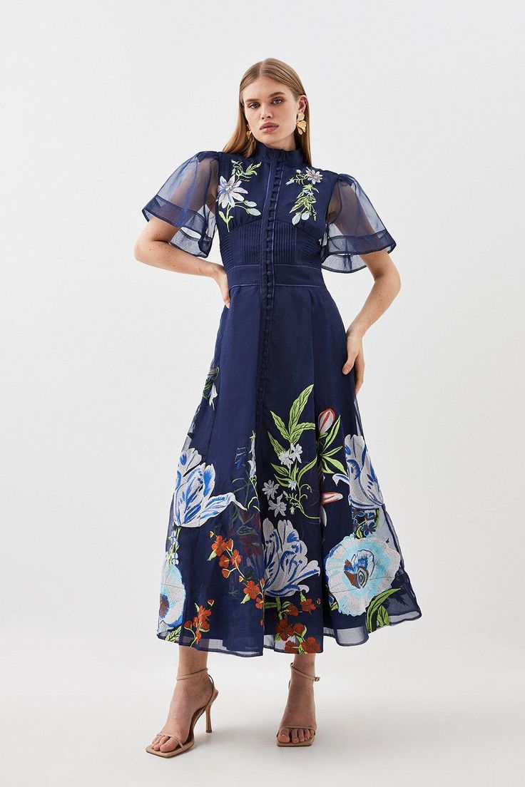 Ornate And Original, This Midi Dress Is Defined By Intricate Embroidery To The High-Neck Bodice, Offset By Semi-Sheer Long Sleeves And Tonal Buttons. Landing At A Delicately-Gathered A-Line Skirt, This Wedding-Ready Piece Calls For Tonal Stilettos And An Artful Floral Headband.High Necktonal Buttonsfloral Embroiderymidi Length Wedding Outfits For Women, Botanical Embroidery, Botanical Motifs, Dark Dress, Angel Sleeves, Fit And Flare Silhouette, Angel Sleeve, Wedding Attire Guest, Guest Attire