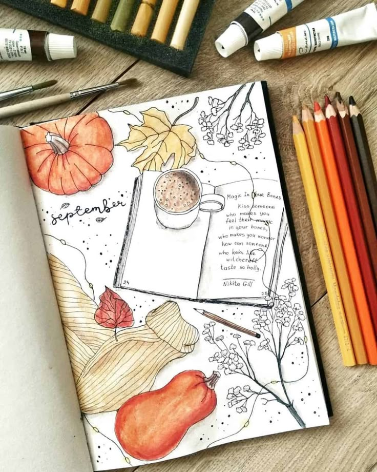 an open notebook with autumn drawings and colored pencils