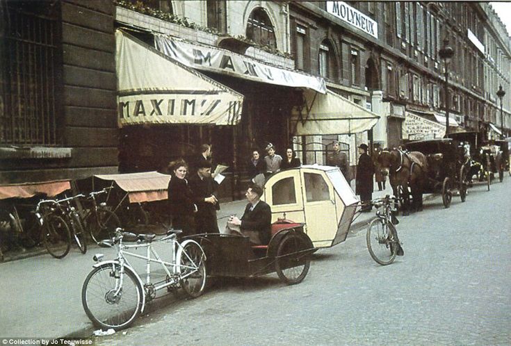 an old photo of people riding in a horse drawn carriage down the street with horses and carriages behind them