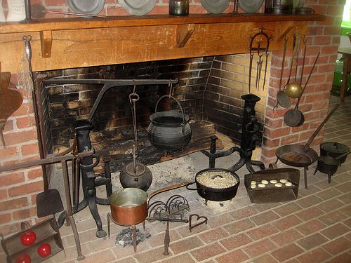 an old fireplace with many pots and pans on it