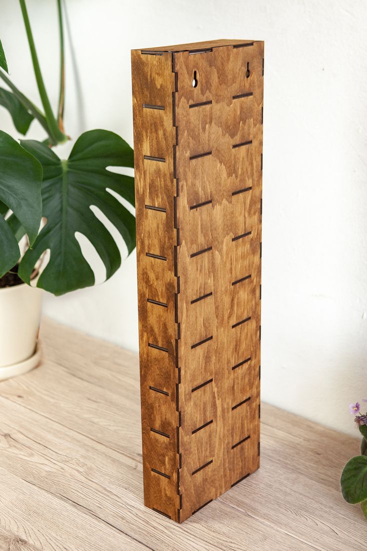 a tall wooden object sitting on top of a table next to a potted plant