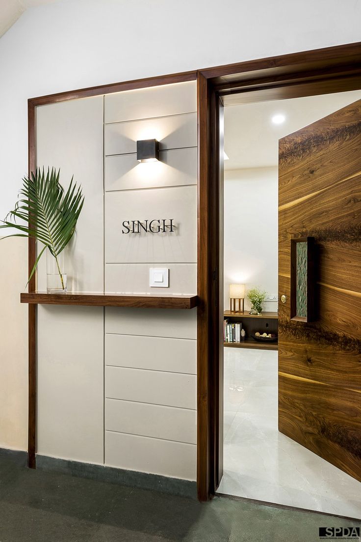 an open door leading into a room with wood paneling and white walls, along with a potted plant