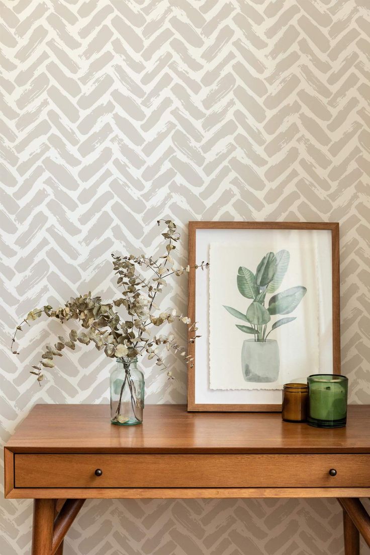 a wooden table topped with a vase filled with flowers next to a wallpapered wall