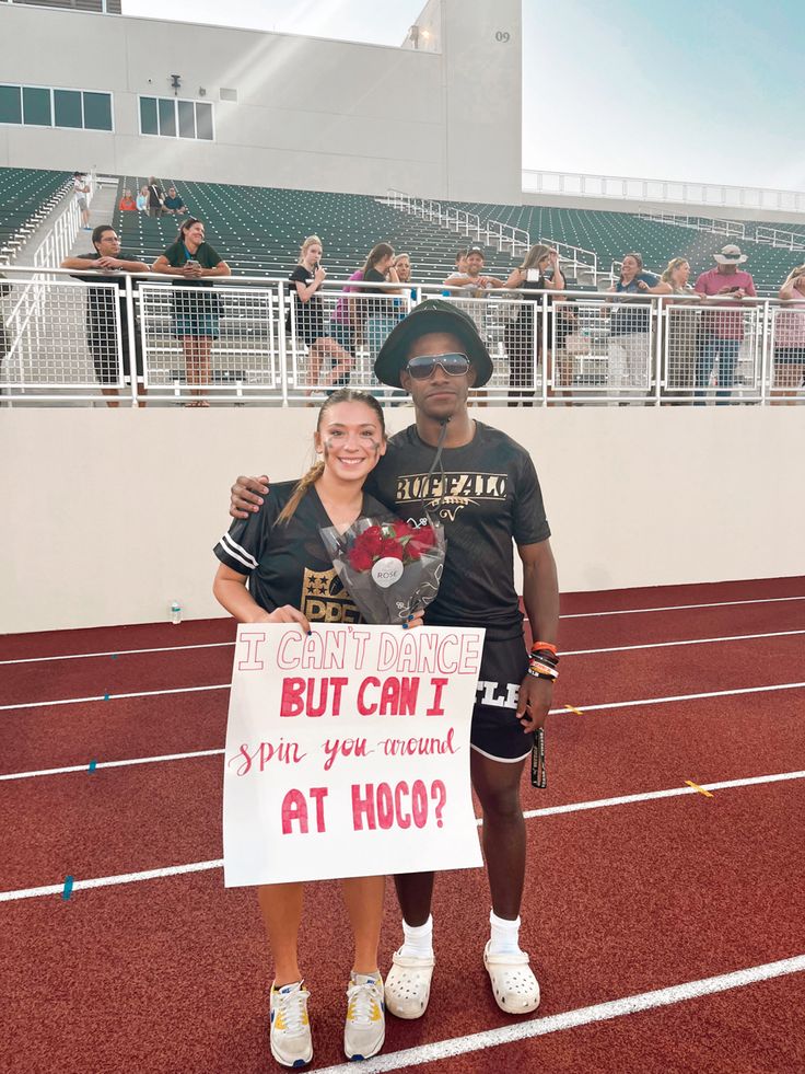 two people standing next to each other on a track with a sign in front of them