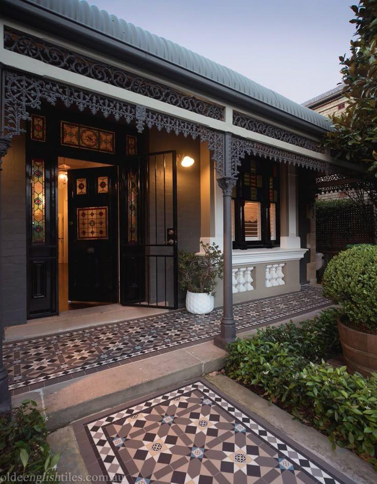 the front entrance to a house with tiled steps and potted plants on either side