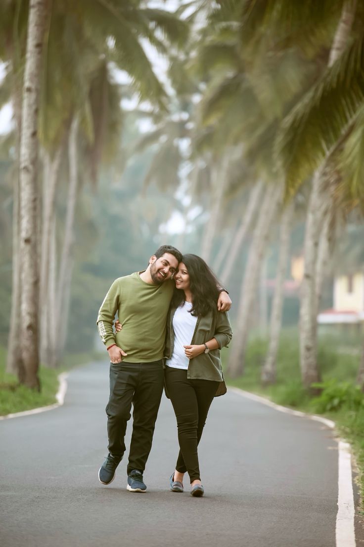 a man and woman are walking down the street with palm trees in the back ground