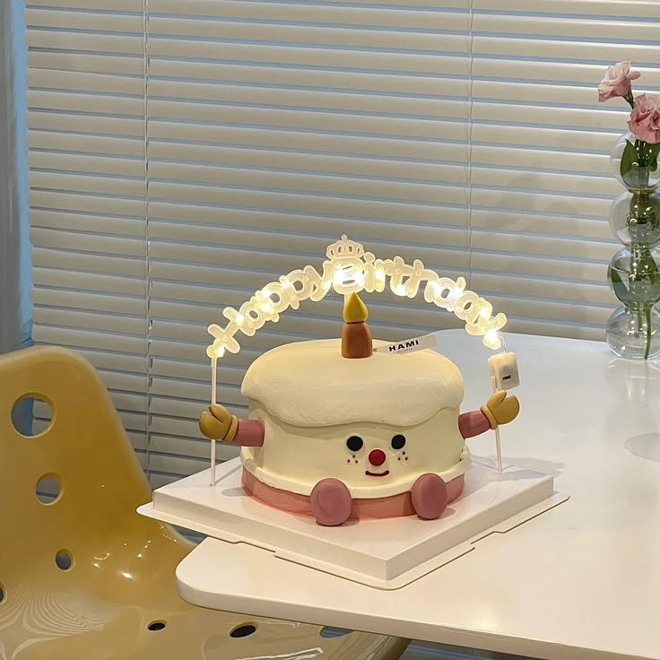 a birthday cake sitting on top of a white table next to a vase with flowers