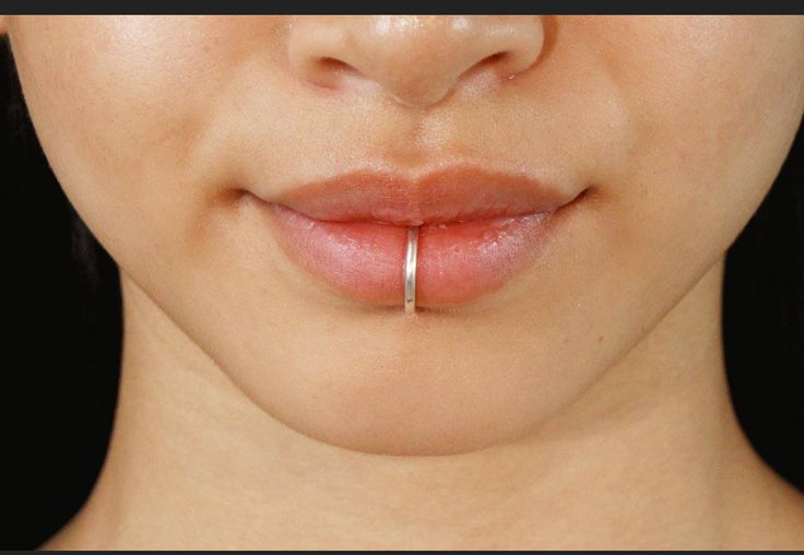 a woman's nose has a ring on it to help her look like she is holding something in her mouth