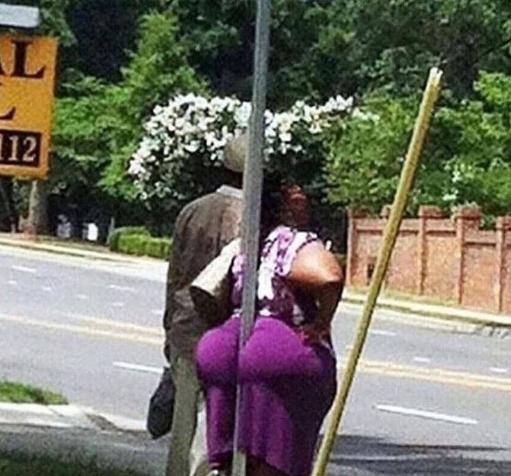 a man and woman leaning against a street sign