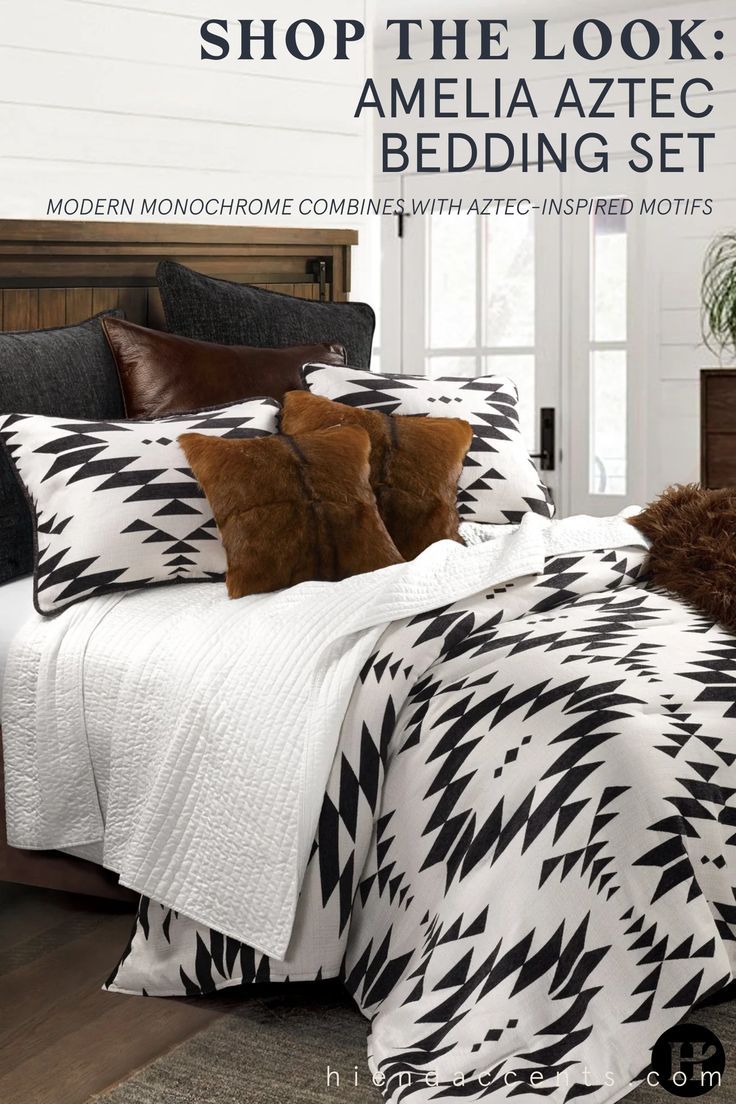 a bed with black and white comforter, pillows and blankets on top of it