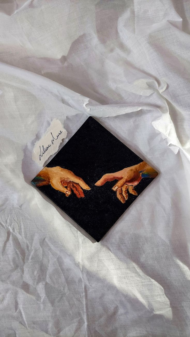 an image of two hands touching each other on a white sheet with writing underneath it