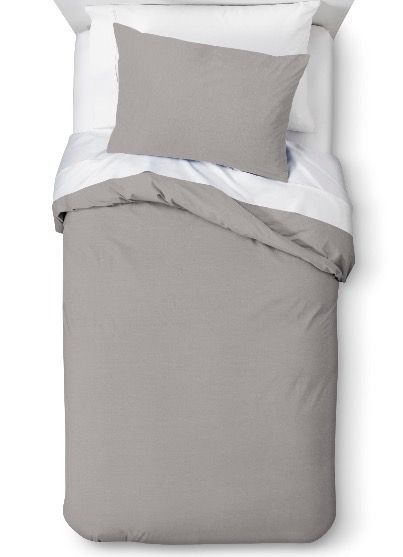 an image of a bed with grey and white sheets