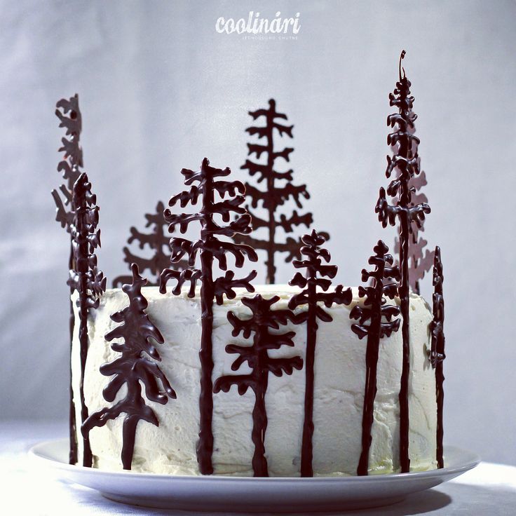 a white cake with chocolate frosting and trees on top is sitting on a plate