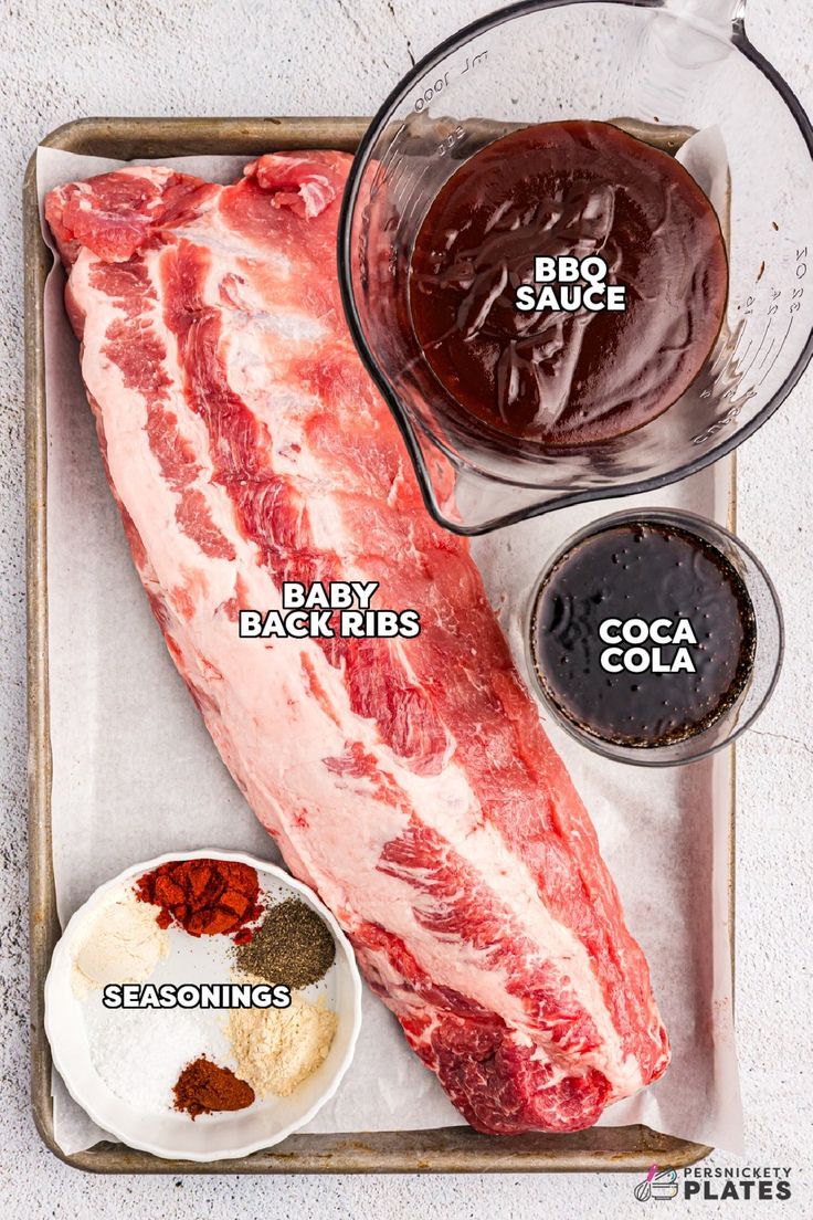 the ingredients needed to make a barbecue ribs recipe on a baking sheet, including bbq sauce and baby back ribs