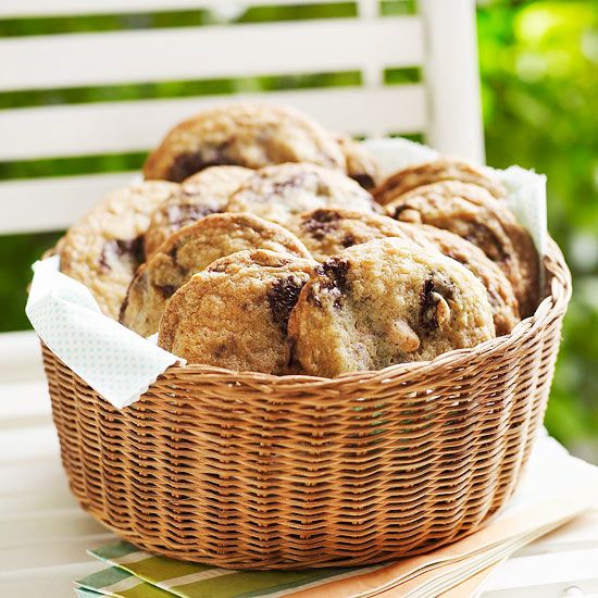 a wicker basket filled with cookies sitting on top of a white table next to a wooden chair