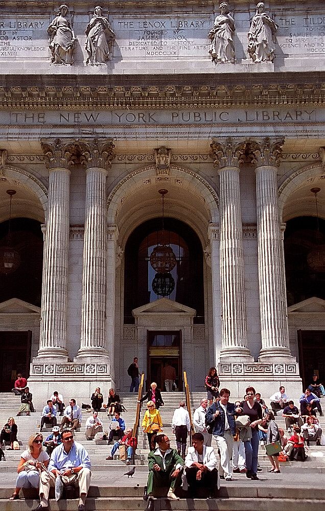 many people are sitting on the steps in front of a building with columns and pillars